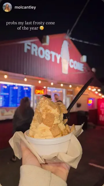 Soft serve cup with cereal pieces in front of the lit-up stand at night