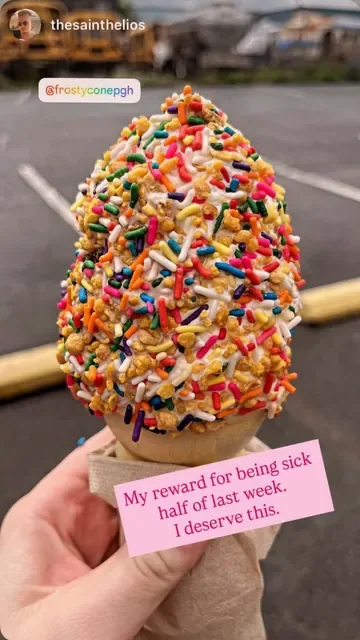 Cone dipped in rainbow sprinkles and crunch, held up in the parking lot